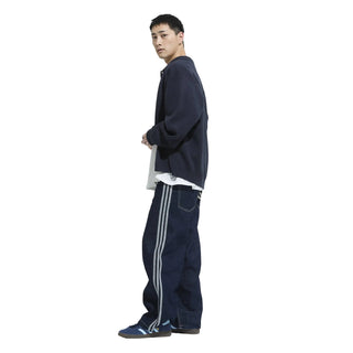 Person wearing a navy tracksuit with white stripes on a white background