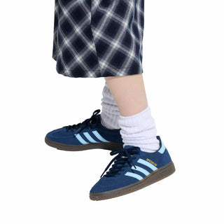 Blue sneakers with white stripes worn with plaid pants and white socks on a white background