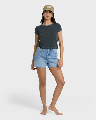 Woman wearing a dark gray t-shirt and light blue denim shorts on a white background
