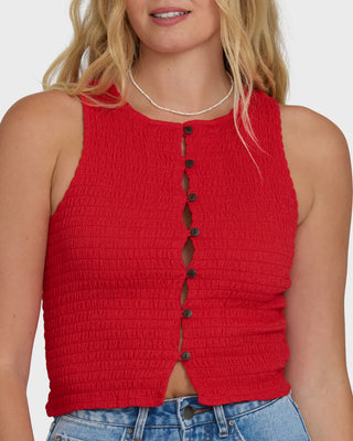 Red sleeveless top with buttons worn by a person on a white background