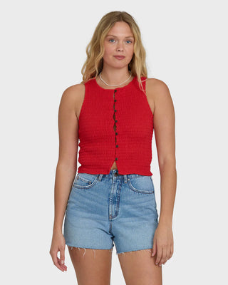 Woman wearing a red sleeveless top and blue shorts on a white background