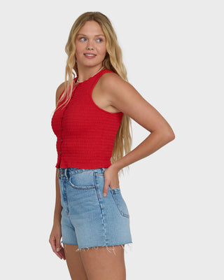 Woman wearing a red sleeveless top and denim shorts on a white background