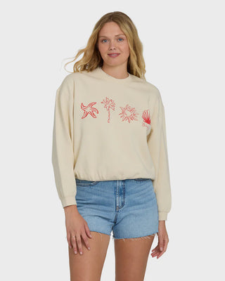 Woman wearing a beige sweatshirt with red graphics and denim shorts on a white background