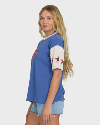 Woman wearing a blue t-shirt with white sleeves and star design on a plain background