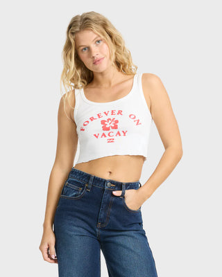 Woman wearing a white tank top with red text and blue jeans on a light gray background