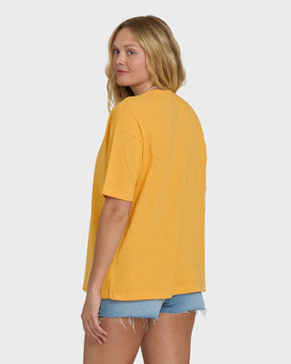 Woman wearing a mustard yellow top and denim shorts on a white background