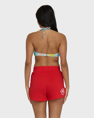 Woman wearing a colorful bikini top and red shorts on a white background