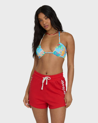 Woman wearing a colorful bikini top and red shorts on a white background