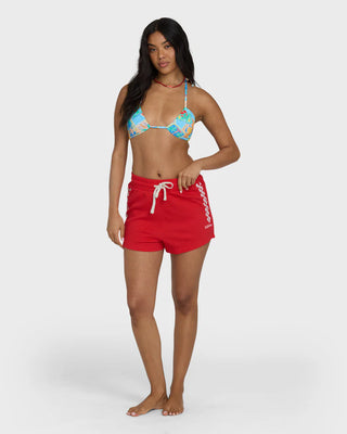 Woman wearing a colorful bikini top and red shorts on a white background