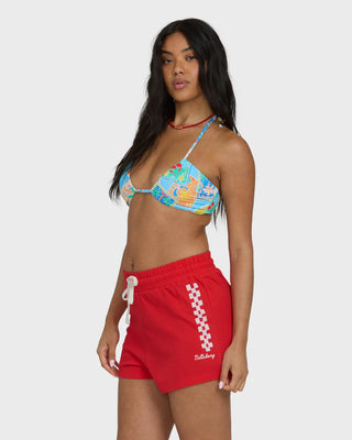 Woman wearing a colorful bikini top and red shorts with a checkered pattern on a white background