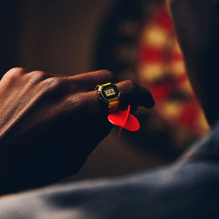 Hand holding a red dart with a vintage watch on a blurred background