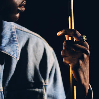Person holding a pool cue against a dark background