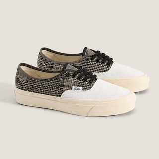 A pair of Vans Authentic low-top sneakers with a textured black and beige snakeskin pattern on the quarter panels, a white suede toe box, black laces, and a cream-colored rubber sole, set against a solid light beige background.