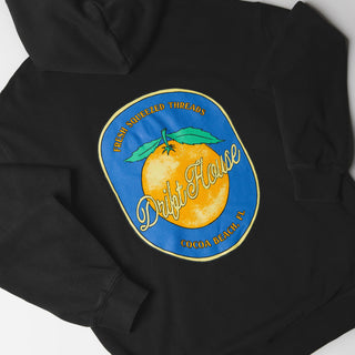Drift House Fresh Squeezed Hoodie in Vintage Black — relaxed garment-dyed 9.4 oz fleece pullover with Florida orange front graphic, "Fresh Squeezed Threads" back print, drop shoulders, and kangaroo pocket
