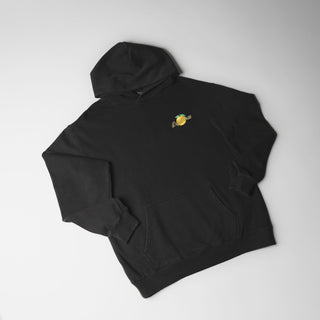 Drift House Fresh Squeezed Hoodie in Vintage Black — relaxed garment-dyed 9.4 oz fleece pullover with Florida orange front graphic, "Fresh Squeezed Threads" back print, drop shoulders, and kangaroo pocket