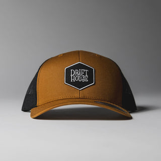 Camel Drift House Hex trucker hat with mesh back and hex logo.