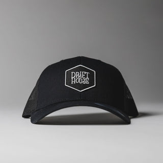 Black Drift House Hex trucker hat with mesh back and hex logo.
