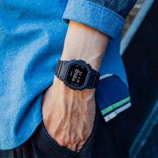 Black digital watch on a wrist with a blue denim background