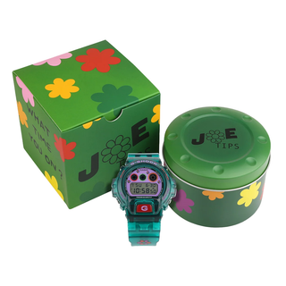 “Jae Tips G-SHOCK watch with translucent teal case and strap, lavender face, multicolor dial accents, flower graphics, and a red front button.”
