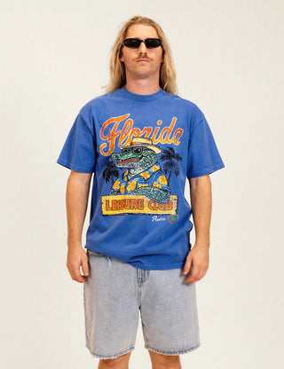 Duvin x Florida Gators Leisure Club Tee with orange Florida lettering and Albert wearing sunglasses and a Hawaiian shirt behind a Leisure Club sign.