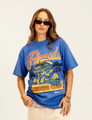 Duvin x Florida Gators Leisure Club Tee with orange Florida lettering and Albert wearing sunglasses and a Hawaiian shirt behind a Leisure Club sign.