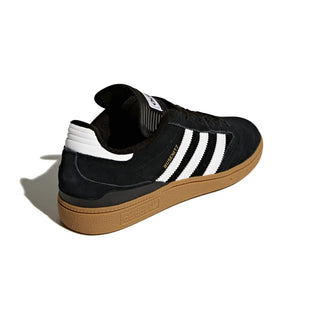 Black Adidas sneaker with white stripes on a light gray background