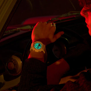 Person wearing a glowing watch inside a vehicle with red interior lighting.