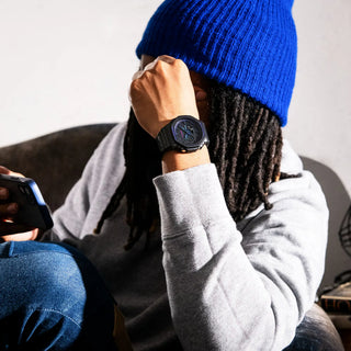 Person wearing a blue beanie and gray sweater, sitting and using a phone.