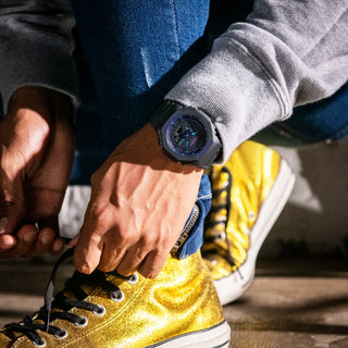 Person tying yellow sneakers with a watch on wrist