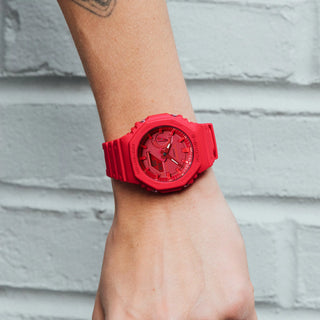 Red watch on a wrist with a gray concrete background