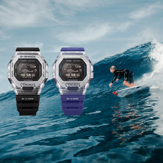 Two Casio G-Shock watches with a surfer in the background on a wave.
