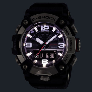 Front view of the G-SHOCK GGB100XMH-5A Mudmaster with a gold-tone bezel, dark brown case and band, black analog-digital dial, and red second hand