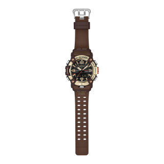 Front view of the G-SHOCK GGB100XMH-5A Mudmaster with a gold-tone bezel, dark brown case and band, black analog-digital dial, and red second hand