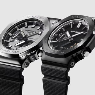 G-SHOCK GM-2100LXB-1A Watch in Black/Gold — CasiOak silhouette with stainless steel case, carbon core guard structure, black IP bezel with gold-tone accents, analog-digital display, 200M water resistant