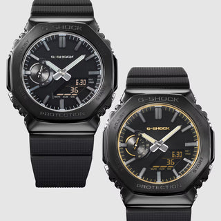 G-SHOCK GM-2100LXB-1A Watch in Black/Gold — CasiOak silhouette with stainless steel case, carbon core guard structure, black IP bezel with gold-tone accents, analog-digital display, 200M water resistant