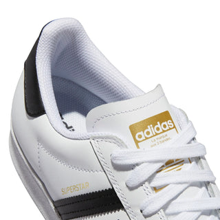 White Adidas Superstar sneaker with gold accents on a white background