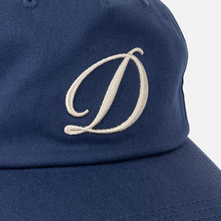 Angled front view of Dime Cursive D Worker Cap in Marine blue with a raised cream embroidered cursive D logo and curved brim