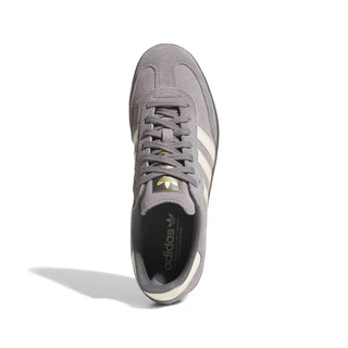 A single Adidas Samba sneaker in gray suede and synthetic mesh, featuring white side stripes, a gold logo patch, and a black interior with the Adidas trefoil logo, shown from a top-down angle on a white background.