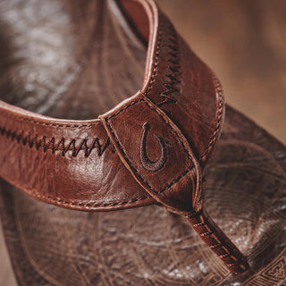 OluKai Hiapo Men's Leather Sandals in Rum/Dark Wood — naturally tumbled marbled full-grain leather with Polynesian whipstitching, moko tattoo footbed, leather-wrapped outsole, and non-marking rubber traction pods