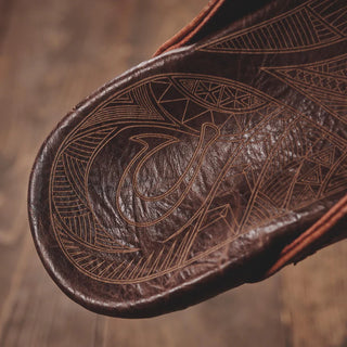 OluKai Hiapo Men's Leather Sandals in Rum/Dark Wood — naturally tumbled marbled full-grain leather with Polynesian whipstitching, moko tattoo footbed, leather-wrapped outsole, and non-marking rubber traction pods