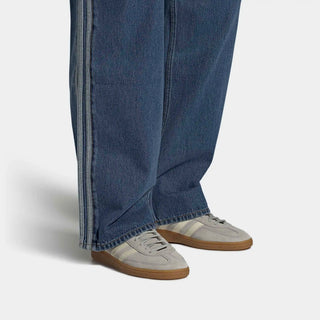 Person wearing blue jeans and gray sneakers on a white background