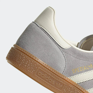 Close-up of a gray and white Adidas sneaker with brown sole on a light gray background