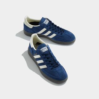 Blue Adidas sneakers with white stripes on a light gray background
