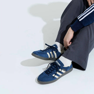 Person wearing blue sneakers with white stripes on a light gray background