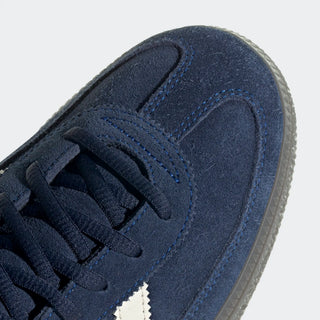 Close-up of a navy blue suede sneaker with white sole on a light gray background