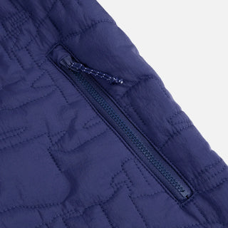 Front view of Dime Reversible Insulated Jacket in Blue Iris with a geometric quilted pattern, hood, zippered pockets, chest logo, and hem cinches