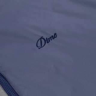 Front view of Dime Reversible Insulated Jacket in Blue Iris with a geometric quilted pattern, hood, zippered pockets, chest logo, and hem cinches