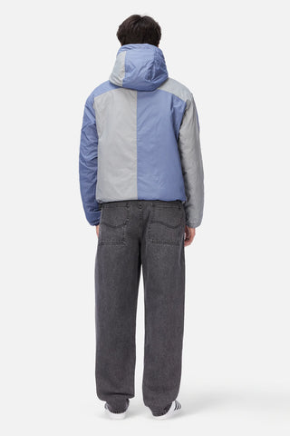Front view of Dime Reversible Insulated Jacket in Blue Iris with a geometric quilted pattern, hood, zippered pockets, chest logo, and hem cinches