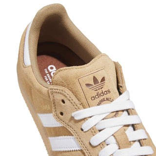 Beige Adidas sneaker with white laces and stripes on a white background