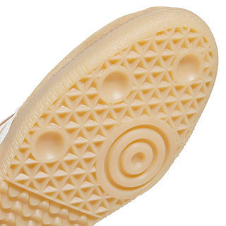 Close-up of a beige textured rubber outsole with a geometric tread pattern and circular center design, shown against a white background.